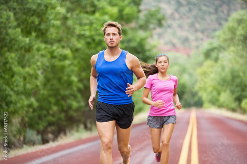 Runners - couple running training marathon on road