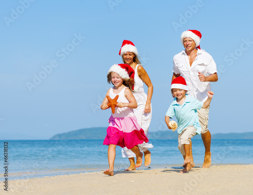 Family running on the beach in Christmas.