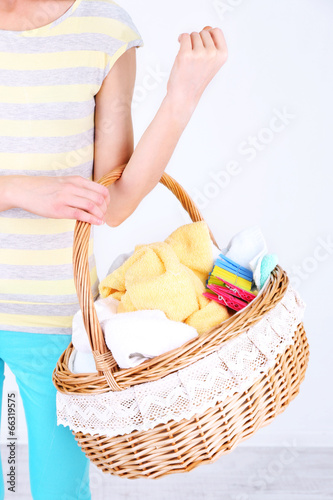 Woman holding laundry basket with clean clothes, towels and