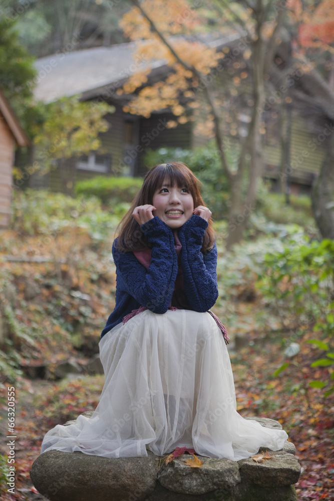 秋の紅葉の公園で座っている笑顔の女性