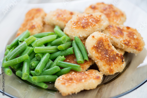 Sesame chicken nuggets with boiled beans, close-up, studio shot