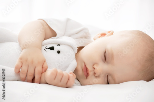 Canvastavla Carefree sleep little baby with a soft toy on the bed
