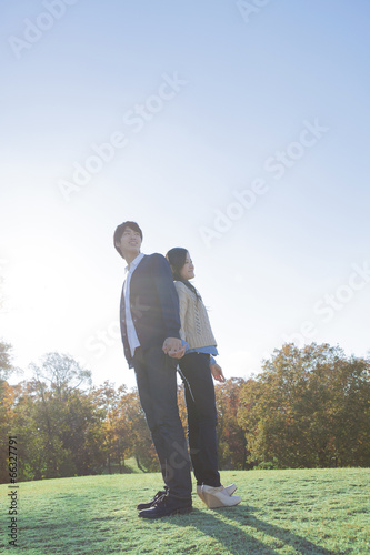 芝生の上で背中合わせするカップル © milatas