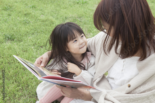 芝生で絵本を読む母と子