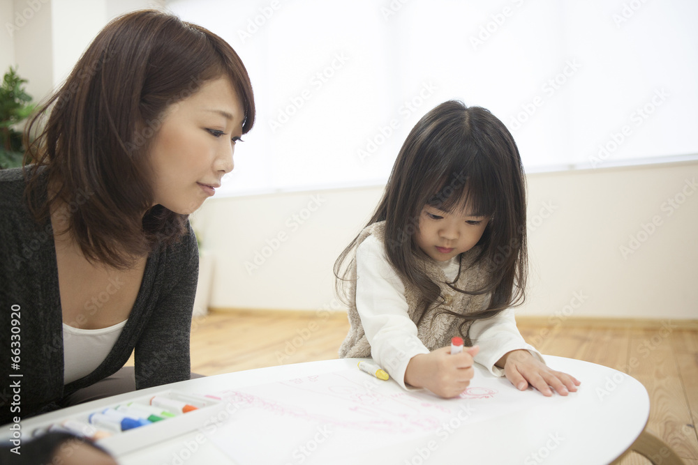 部屋でお絵描きをする母と子
