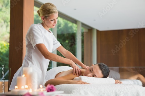 Smiling brunette getting a shoulder massage