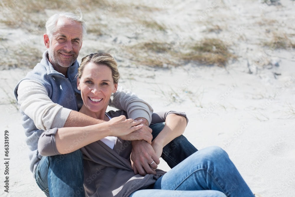 Obraz premium Attractive couple smiling at camera on the beach