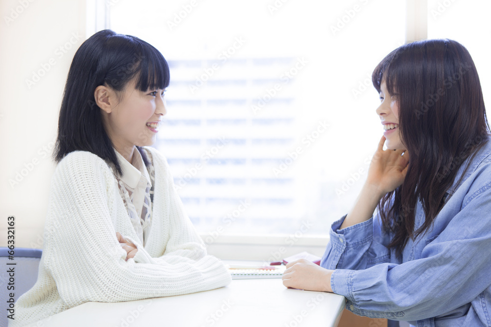 教室で友達と会話する女子学生
