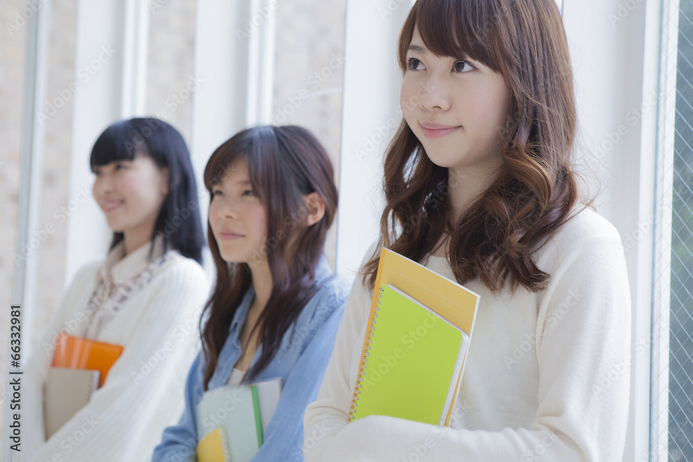 ノートを持って3人で並ぶ女子学生 ノートを持って3人で並ぶ女子学生