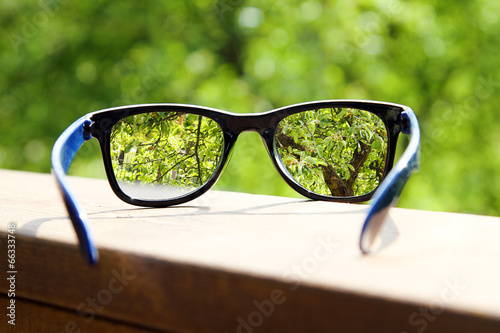 eyeglasses in the hand over blurred tree background