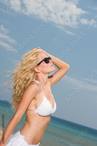 Young woman in white bikini holding sarong on the beach © Netfalls