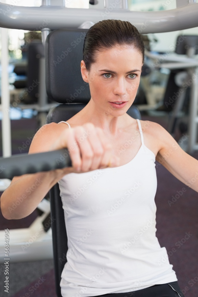 Fit brunette using weights machine for arms Fit brunette using weights machine for arms