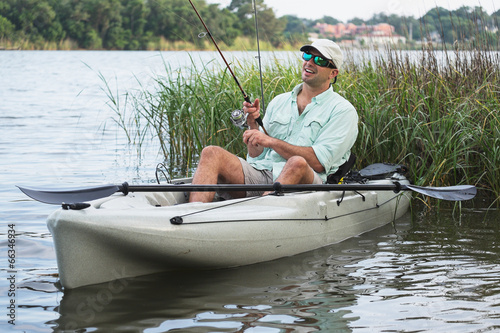 Man Fishing in Kayak in grassy waters