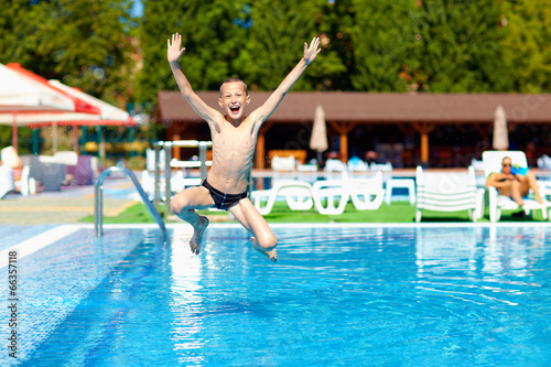 excited teenage boy jumping in the pool