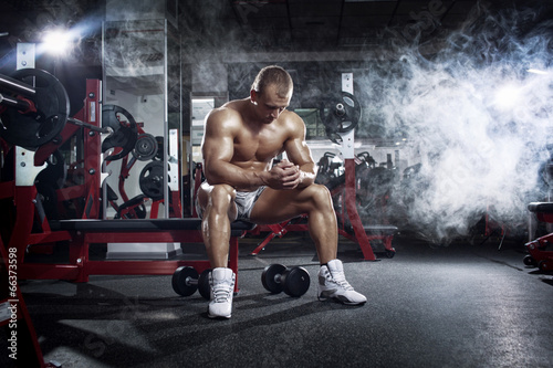 Принти на полотні bodybuilder athletic guy relaxing after workout in gym