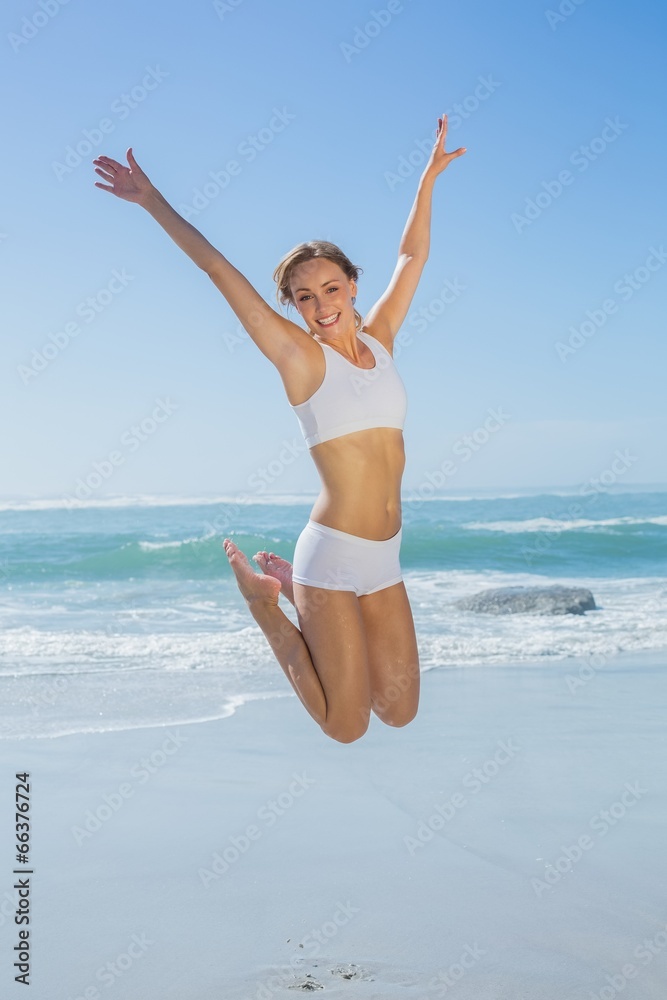Gorgeous fit blonde jumping by the sea with arms out Gorgeous fit blonde jumping by the sea with arms out