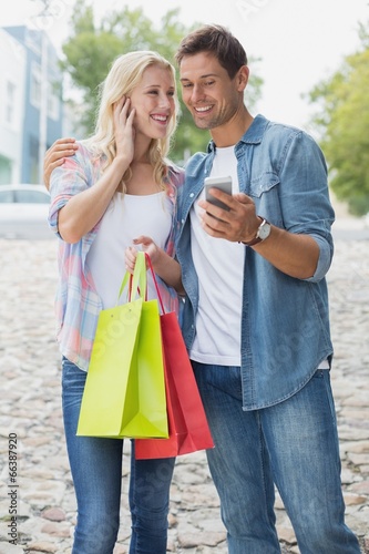 Hip young couple looking at smartphone on shopping trip