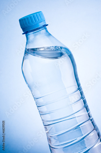 Close-up plastic bottle of drinking water obliquely on a blue ba photo