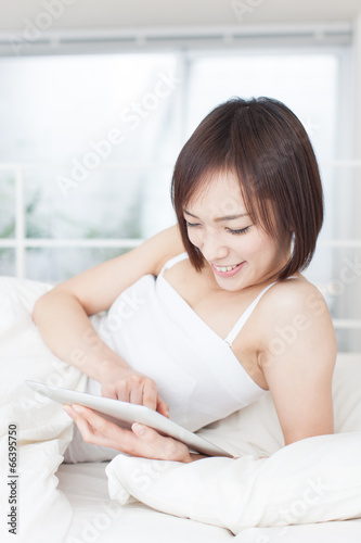ベッドでタブレットPCを使う女性