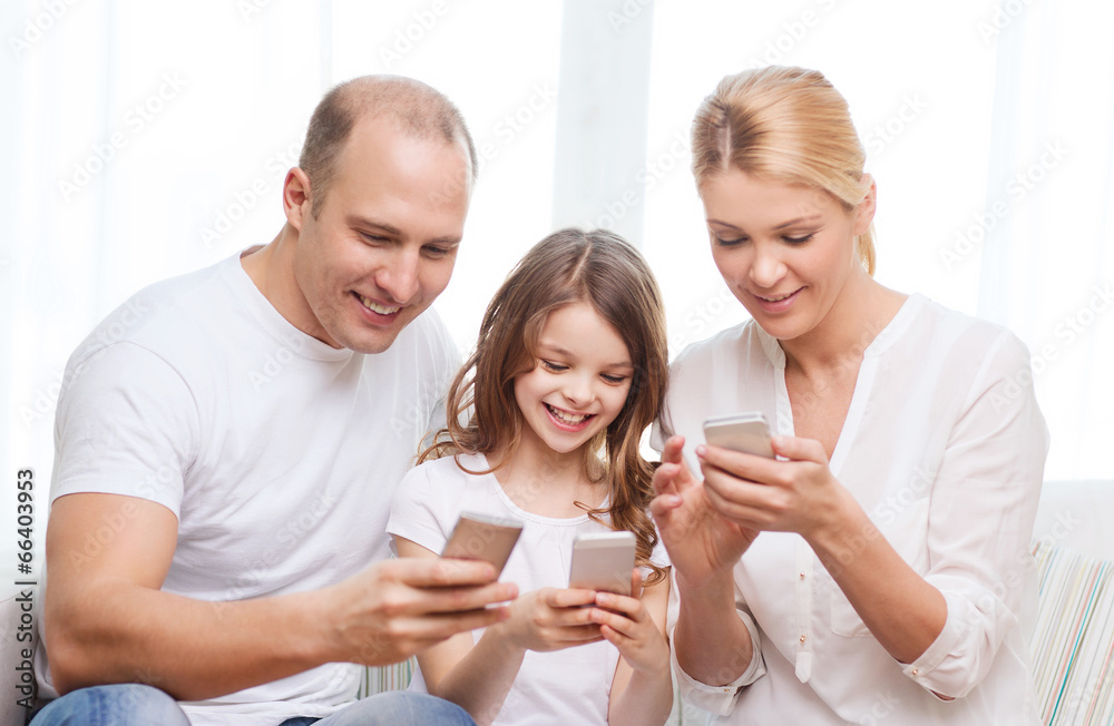 parents and little girl with smartphones at home