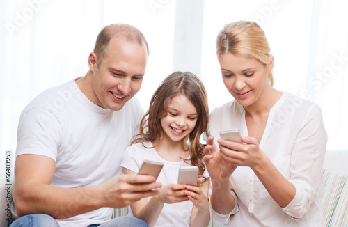 parents and little girl with smartphones at home
