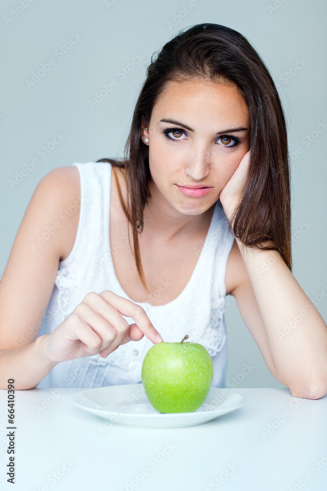 upset brunette woman with green apple on a plate upset brunette woman with green apple on a plate