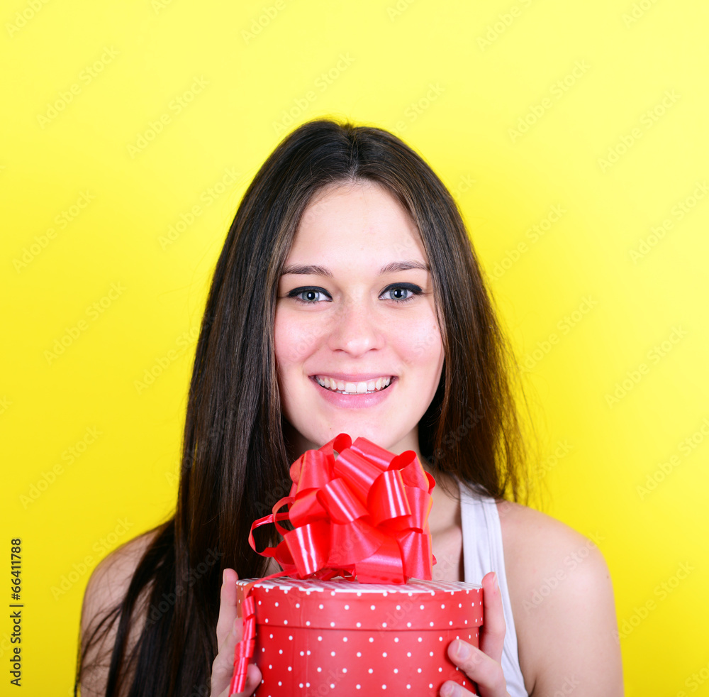 Portrait of happy woman opening gift box against yellow backgrou Portrait of happy woman opening gift box against yellow backgrou