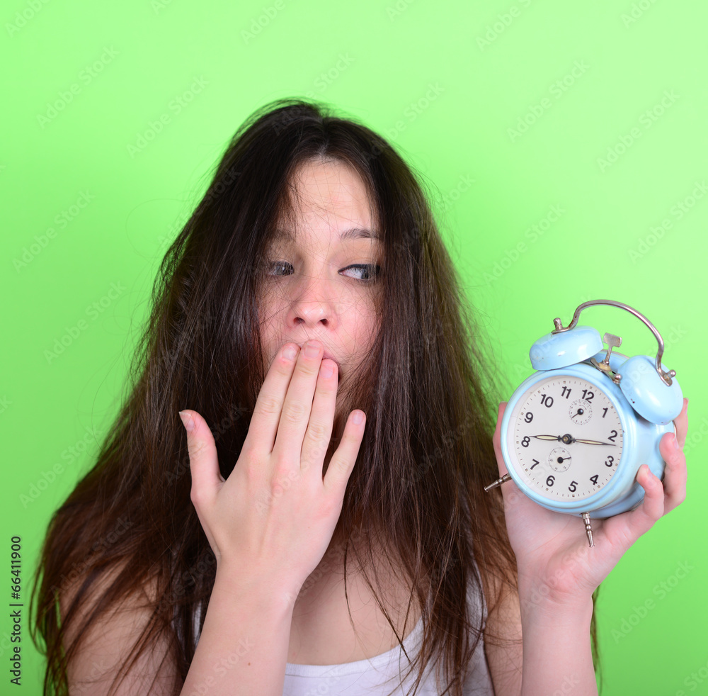 Portrait of sleepy young female in chaos holding clock against g Portrait of sleepy young female in chaos holding clock against g