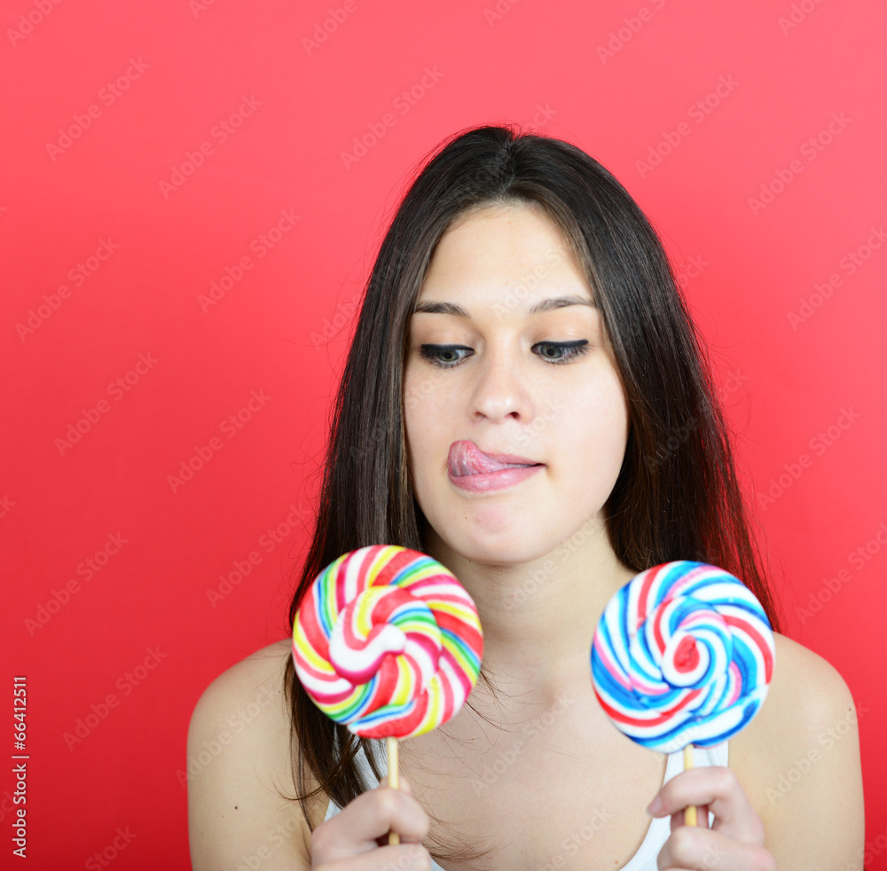 Portrait of woman holidng lollipops against red background