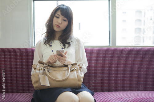 電車でスマートフォンを見る女性 photo