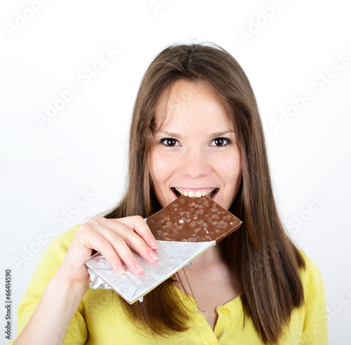 Young woman eating chocolate bar against white background
