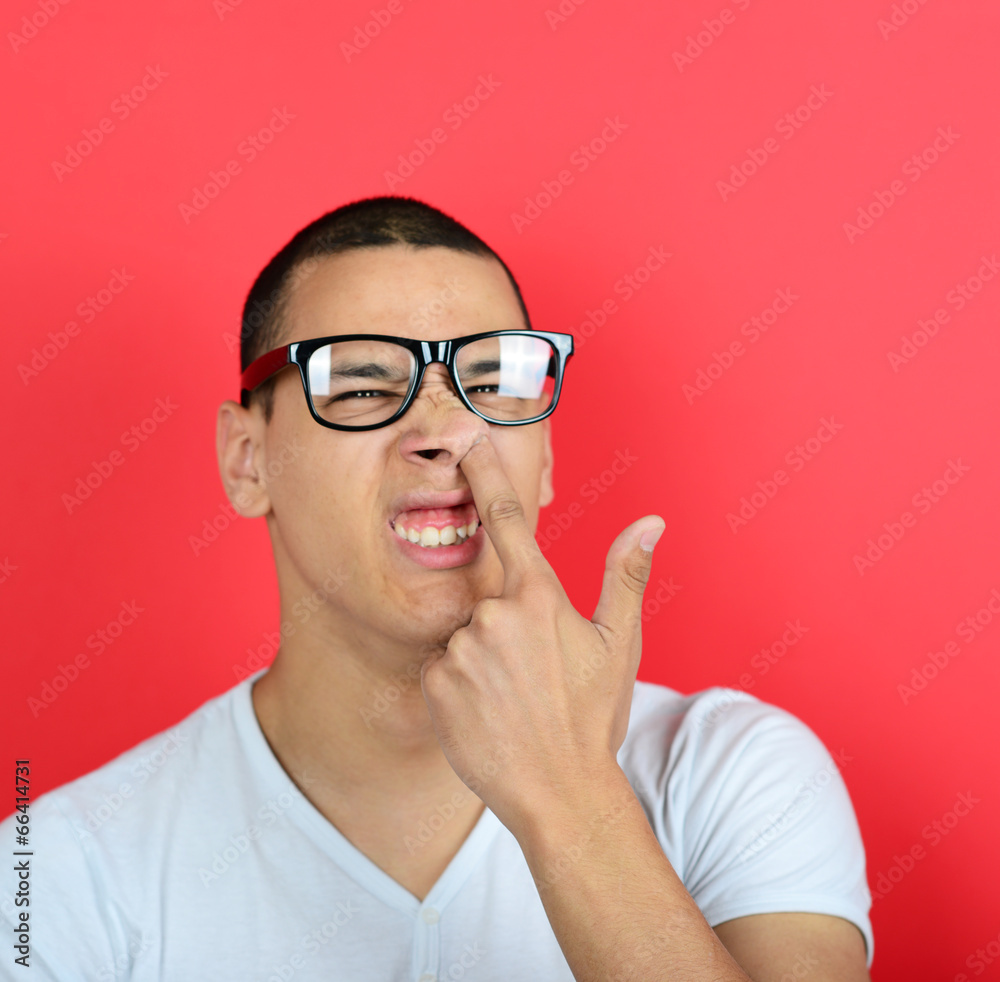 Portrait of a funny guy with finger in his nose against red back