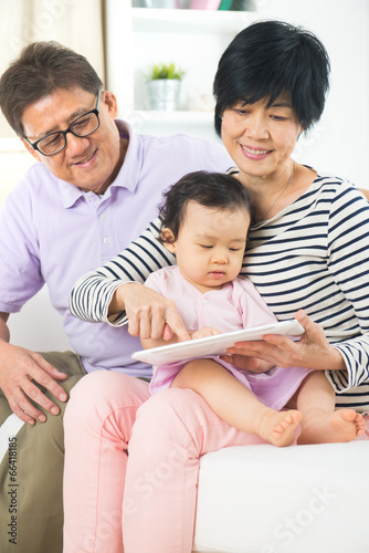 asian grand parents teaching grand son internet with a tablet