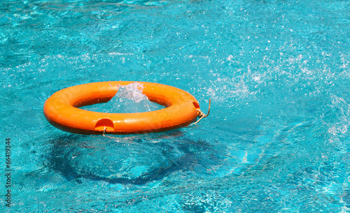 Orange life buoy floating on the surface of blue water