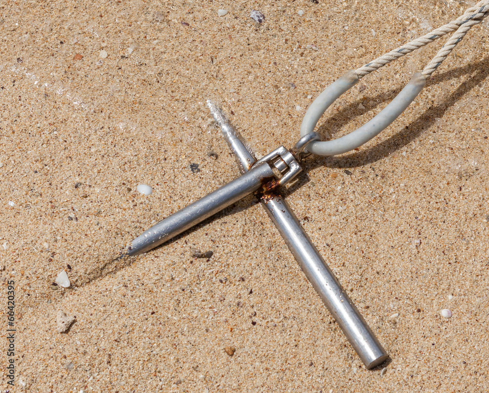 Obraz premium Metal anchor with rope fixed in the sand at seashore