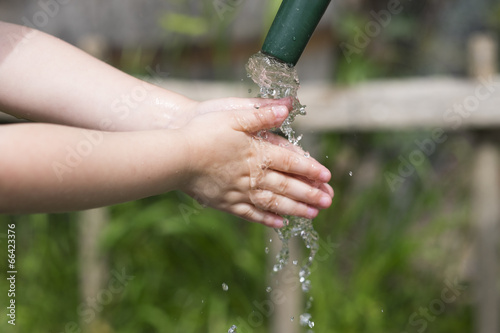 A child washes hands in the garden