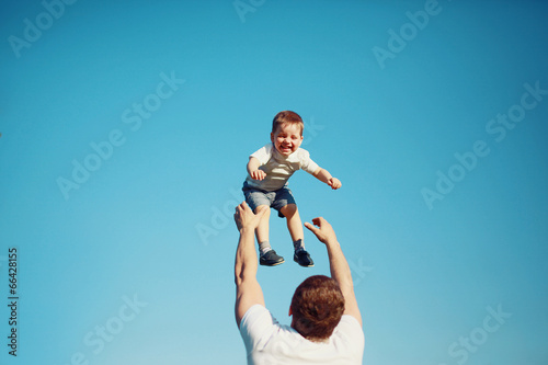 Happy joyful child, father fun throws up son in the air