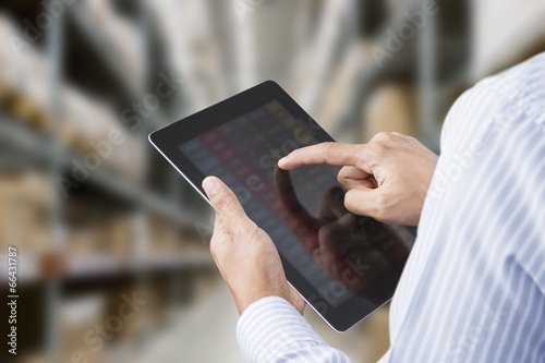 Businessman checking inventory in stock room on tablet photo
