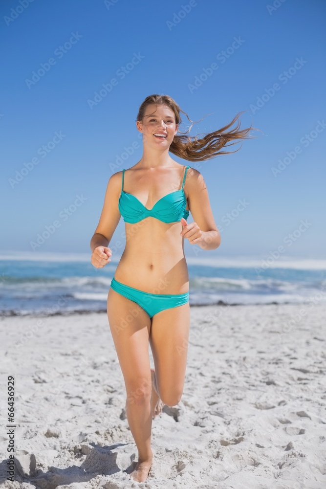 Fit woman in bikini jogging and smiling