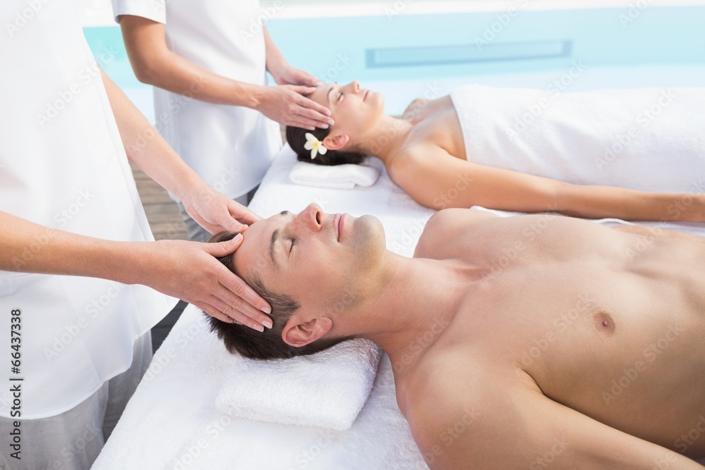 Content couple enjoying head massages poolside
