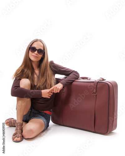 Girl sitting near a suitcase, isolated on white