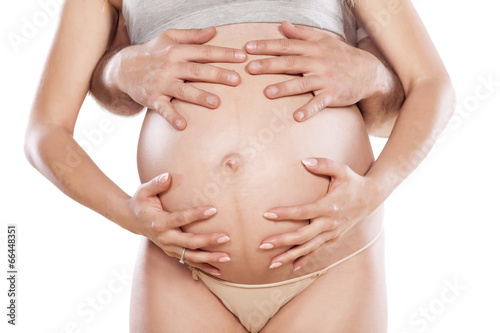 male and female hands on the stomach of pregnant woman