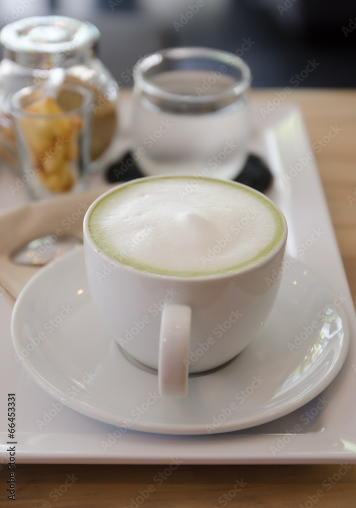 Green tea with milk , sugar, biscuit and drinking water Green tea with milk , sugar, biscuit and drinking water