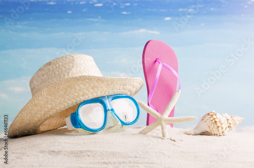 Straw hat, snorkel mask and flip flops on a tropical beach 