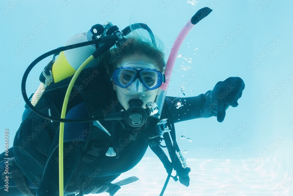 Woman on scuba training submerged in swimming pool showing thumb Woman on scuba training submerged in swimming pool showing thumb