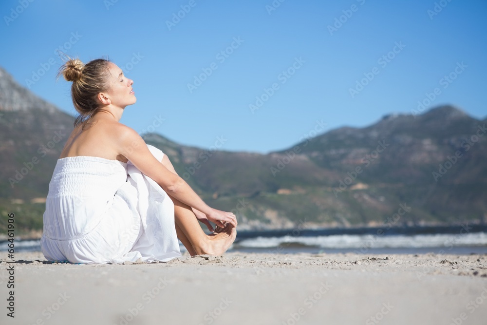 Content blonde in white dress sitting on the beach Content blonde in white dress sitting on the beach