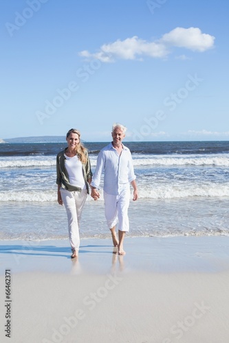 Happy couple strolling barefoot on the beach