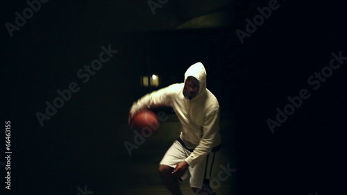 Basketball player dribbling the ball at night