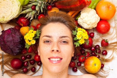 Smiling female face surrounded with lot of fruit and vegetables