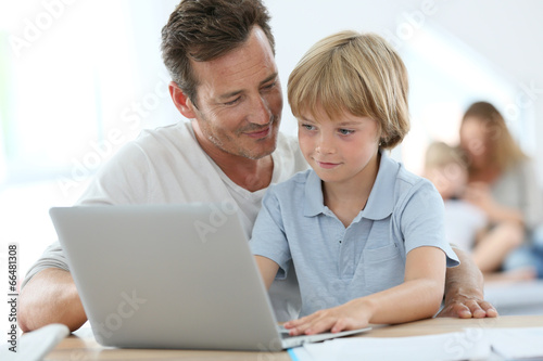 Man with little boy playing on laptop computer © goodluz